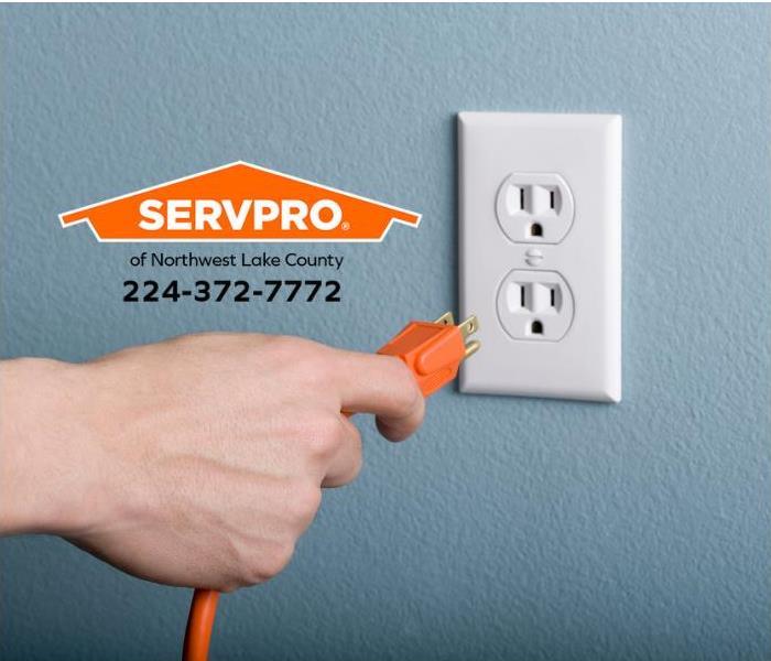 A hand is plugging a cord into an electrical outlet.